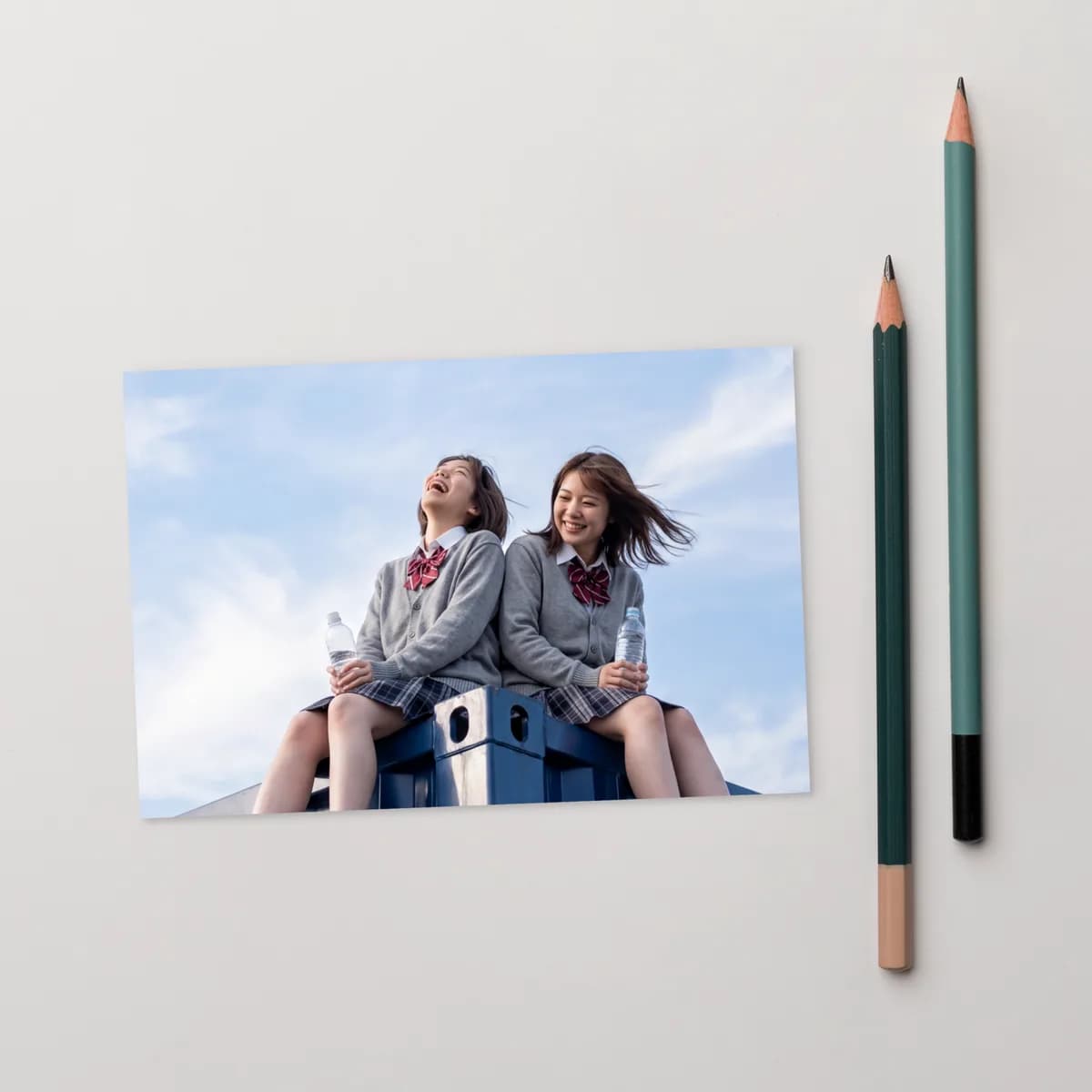 A CFTH postcard artwork on a white desk beside two pencils